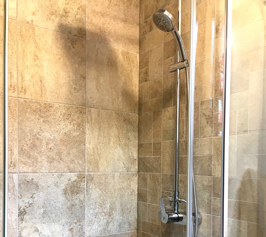 Detail koupelny s dekorem kamene, sprchová hadice.